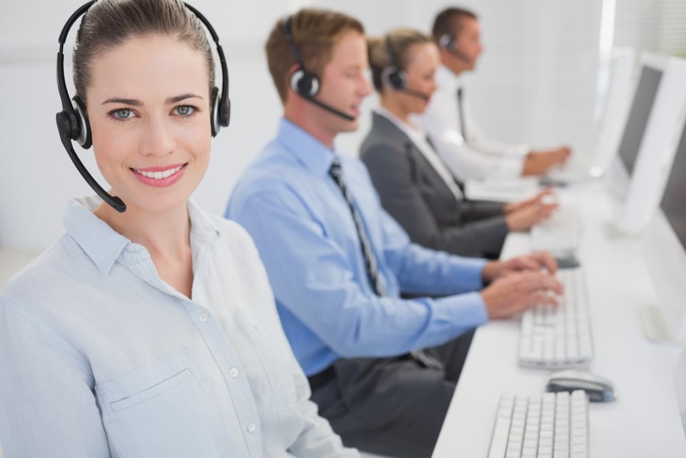 Business team working on computers and wearing headsets in call center
