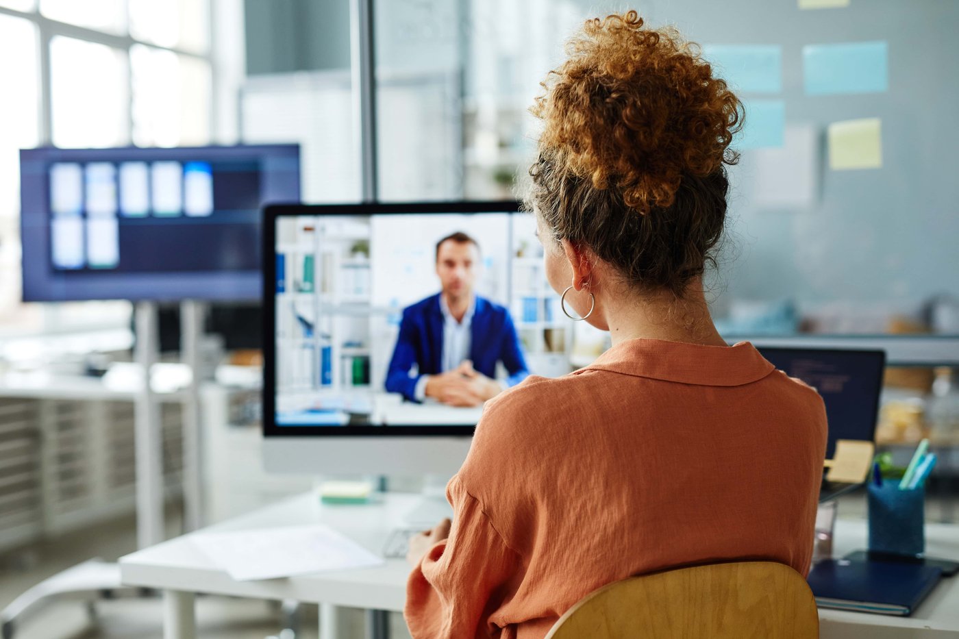 Rear view of businesswoman having online meeting on computer_517787169_Preview