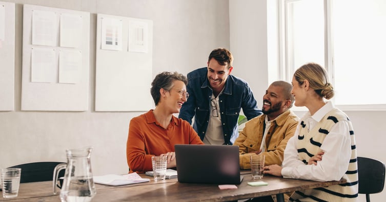 Group of people discussing project, smiling in office.